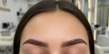 Mujer con cejas perfectamente diseñadas combinando microblading y microshading, en un entorno de salón de belleza moderno.