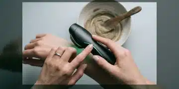 Mãos segurando um dispositivo de beleza futurista com luzes verdes, em contraste com uma tigela de argila natural desfocada, simbolizando a armadilha da solução mágica em beleza.